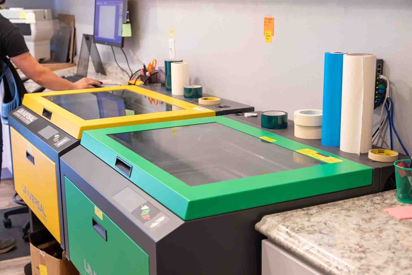 A laser engraver at work at Capital Trophy, with the order on screen beside it